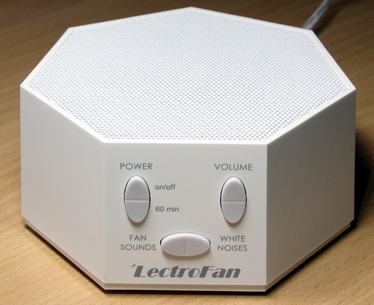 White noise machine on a nightstand beside a bed